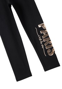 Leggings neri con una stampa di paillettes rosa oro lucido che recita "PARIS c'est la vie", caratterizzati da una texture di tessuto liscia e una vestibilità aderente.
