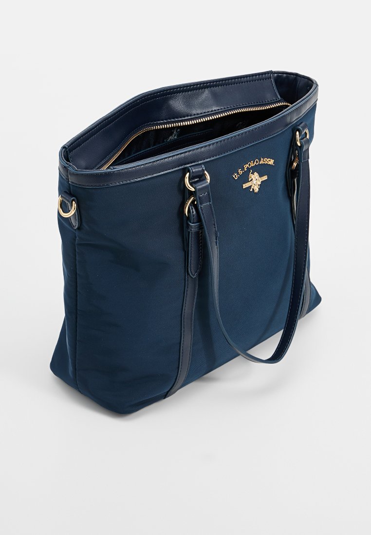 Sac fourre-tout bleu marine avec logo doré, deux poignées, fermeture éclair et tissu texturé. L'intérieur a une doublure lisse.