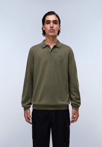 Olijfgroene longsleeve polo met een kraag, één knoop en geribbelde zoom. De stof lijkt soepel en lichtgewicht te zijn.