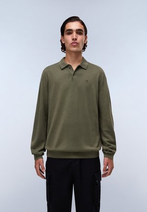 Olijfgroene longsleeve polo met een kraag, één knoop en geribbelde zoom. De stof lijkt soepel en lichtgewicht te zijn.