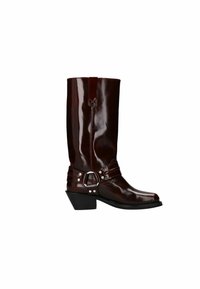 Bottes en cuir brunes, brillantes, montantes jusqu'au genou, avec un bout pointu, des sangles décoratives, des accents métalliques et un talon bas et incliné.