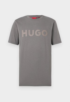 Hall halli lühikeste varrukatega ümara kaelusega T-särk beeži "HUGO" logoga, mis on rinnal trükitud, taust on ühevärviline.