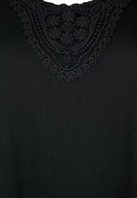 Czarna tkanina z misternymi koronkowymi detalami, z kwiatowymi i okrągłymi wzorami wokół dekoltu w kształcie litery V.