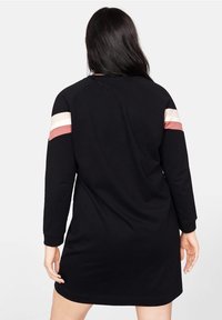 Vestido sudadera negro de manga larga, con rayas en bloques de color rosa y crema en los hombros. Material suave, corte casual.