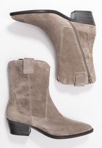 Taupe suede enkellaarzen met een spitse neus, een zijrits en een lage, gestapelde hak. Kenmerkt zich door strakke lijnen en een contrasterende zwarte zool.