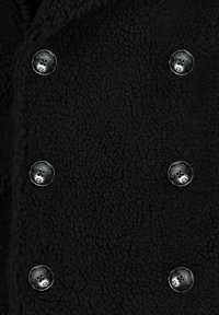 Zwarte fleece jas met een gestructureerd oppervlak en zes metalen knopen met een logo. Het ontwerp heeft een dubbele sluiting.