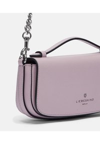 Jasnofioletowa skórzana torebka o fakturowanym wykończeniu, z czarnym wykończeniem i srebrnym łańcuszkiem. Zawiera logo z przodu.