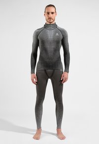 Enganrierter schwarzer und grauer Rash Guard mit hohem Kragen, langen Ärmeln und nahtlosem Design; kombiniert mit passender Leggings, die eine subtile Farbverlauf-Textur aufweisen.