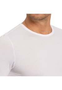 Hvid kort�ærmet T-shirt i et blødt, strækbart stof med en klassisk rund halsudskæring og en glat tekstur, tætsiddende til kroppen.