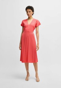 Pink knee-length dress featuring a V-neck, short flutter sleeves, and a fitted waist, made from lightweight, smooth fabric.