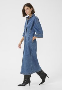 Pikk teksadress, millel on struktureeritud krae, kitsenevad varrukad, küljetaskud ja esi lukk. Kombineeritud mustade teravate kontsadega saapadega.