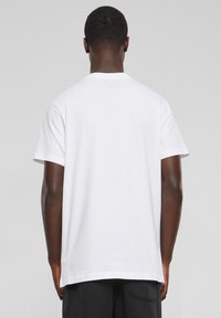 Hvitt bomulls t-skjorte med korte ermer, rund hals og rett snitt. Stoffet virker glatt og lett.