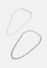 Deux colliers : l'un avec des perles blanches rondes, l'autre en métal argenté, présentant des formes liées et un fermoir avec une chaîne ajustable.