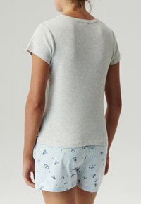 Szara bawełniana koszulka z krótkim rękawem w połączeniu z jasnoniebieskimi szortami z motywem motyla, widocznymi szwami i luźnym krojem.