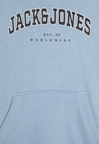 Felpa azzurra con tasca frontale; presenta testo nero che recita "JACK&JONES" e "EST. 90 WORLDWIDE" in uno stile audace e arcuato.
