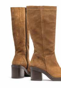 Botas de ante marrón hasta la rodilla con cremallera, tacón alto apilado y costuras de contraste en la suela. Acabado suave con un exterior texturizado.