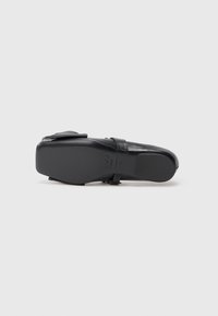 Sandal negru din piele cu un finisaj neted, curea ajustabilă și talpă plată. Baza prezintă branding și un design elegant, minimalist.