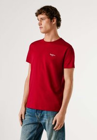 Rood katoenen t-shirt met een ronde hals en korte mouwen, met een klein wit logo op de linkerborst en een losse pasvorm.