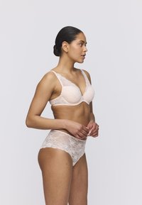 Jasnoróżowy koronkowy stanik z wyściełanymi miseczkami i szerokimi ramiączkami, w zestawie z pasującymi koronkowymi majtkami o wysokim stanie z kwiatowym wzorem i przezroczystą teksturą.