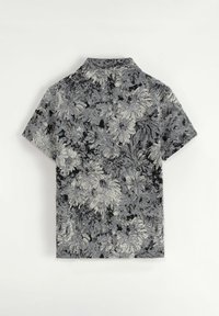 Chemise à manches courtes en motif floral noir et blanc, dotée d'un col et d'un tissu texturé avec divers motifs de fleurs.