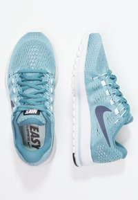 Světle modré sportovní boty s prodyšným síťovaným svrškem, bílou mezipodešví a tmavě modrým logem Nike; s šněrováním a texturovanou podrážkou.