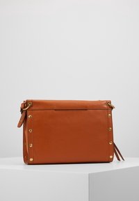 Brun læderhandtaske med guldfarvet hardware, rektangulær form, sidelameller og en aftagelig rem. Glat tekstur og minimalistisk design.