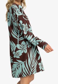 Robe à manches longues en velours côtelé marron avec un imprimé floral tropical bleu clair. Dotée d'un col à boutonnière et d'une coupe décontractée.