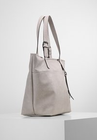 Szara skórzana torba typu tote z regulowanym paskiem, charakteryzuje się gładką fakturą, minimalistycznym designem oraz detalem w postaci przedniej kieszeni.