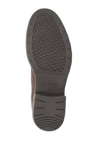 Brązowy skórzany but z trwałą gumową podeszwą, posiadający teksturowany wzór bieżnika oraz wytłoczone logo "Clarks". Kształt jest smukły i casualowy.