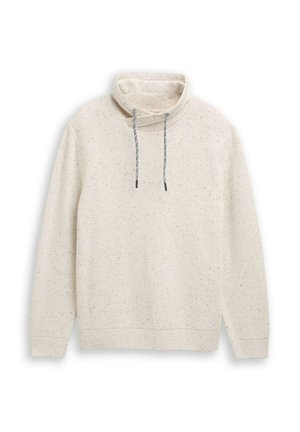 Jasno beżowy sweter z wysokim kołnierzem, prążkowaną teksturą, wzorem w drobne plamki i szarymi sznurkami. Długie rękawy i luźny krój.