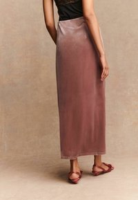 Samtenes Maxirock in sanftem Mauve mit glatter Textur und geradem Schnitt. Kombiniert mit pinkfarbenen Riemchensandalen.