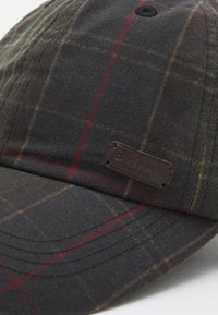 Zwarte en grijze geruite pet met een bruin leren logo label. Kenmerkt zich door een gebogen rand en gestikte details. Materiaal lijkt textuur te hebben en duurzaam te zijn.
