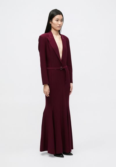 Pikk burgundiapunane kleit sügava V-kaelusega, istuva bodi ja kellukjalt lõheneva seelikuga, sobiva vööga. Valmistatud siledast, hästi vormitavast kangast.