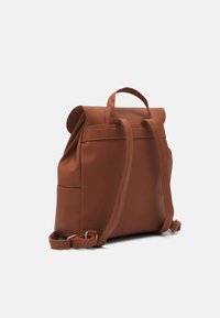 Sac à dos en cuir marron avec des bretelles réglables, une poignée supérieure et une fermeture à rabat sur un fond blanc uni.
