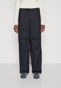 Pantalons cargo amples de couleur marine, dotés de deux poches latérales, d'une taille ajustable avec cordon de serrage et d'un tissu texturé.