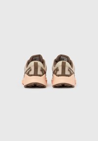 Καφέ και κρεμ αθλητικά παπούτσια με υφή, ροζ σόλα και καφέ καμουφλάζ λεπτομέρειες στη φτέρνα.