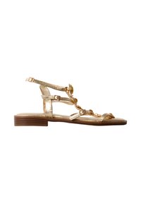 Sandale plate dorée avec plusieurs fines lanières, pierres décoratives, boucle à la cheville et petit talon en bois.