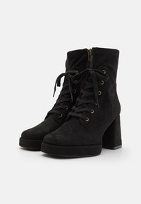Bottines en suède noir avec un devant à lacets et des œillets dorés. Elles possèdent une fermeture éclair latérale et un talon bloc chunky pour plus de hauteur.