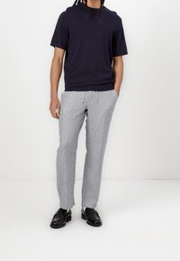 T-shirt à manches courtes bleu marine associé à un pantalon gris clair à rayures. Le pantalon possède une taille élastique avec un cordon de serrage, porté avec des chaussures en cuir noir.