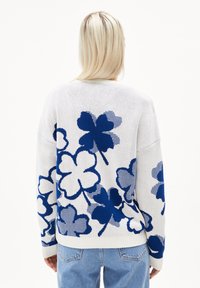 Weißer Strickpullover mit blauem Blumenmuster; hat einen übergroßen Schnitt, gerippte Bündchen und Saum. Das strukturierte Garn verleiht dem Design Tiefe.