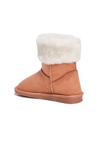 Botín de tobillo de ante color beige con un suave puño de piel sintética blanca, suela plana y costuras sencillas a lo largo de las costuras. Diseño de punta redondeada.