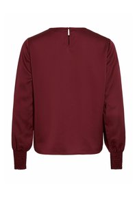 Top borgogna a maniche lunghe realizzato in tessuto liscio, con apertura a chiave sulla schiena e polsini arricciati per dettagli e texture.