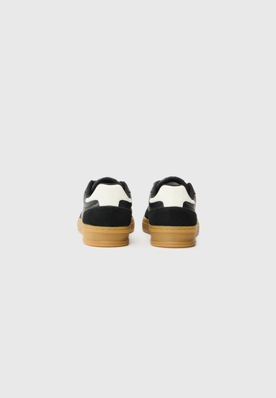 Schwarze Wildledersneaker mit weißen Lederakzenten und gummierten Gummisohlen, ausgestattet mit einer runden Zehenpartie und gepolstertem Kragen.
