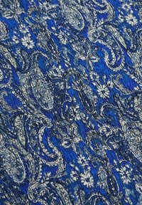 Tela azul con patrones que presentan intrincados diseños florales y de paisley en blanco, con una superficie texturada y arrugada para mayor profundidad.
