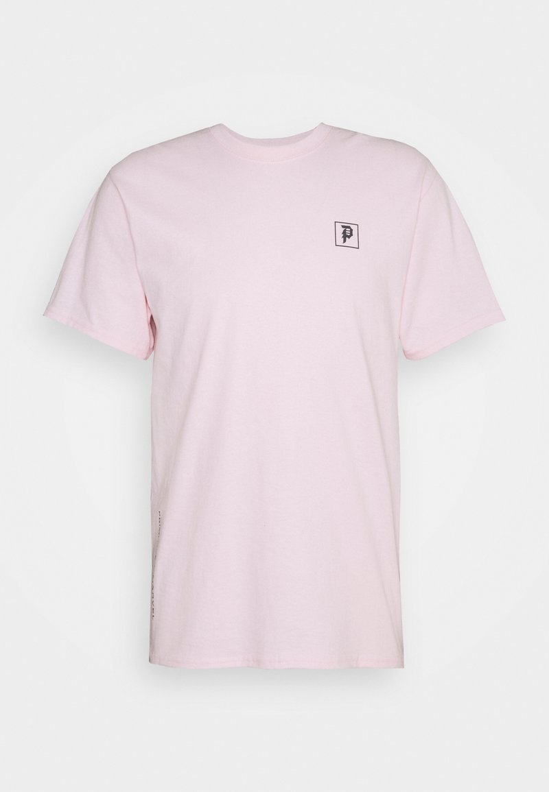 Camiseta de algodón de color rosa claro con mangas cortas, escote redondo, presenta un pequeño logotipo negro en un cuadrado en el lado izquierdo y un detalle lateral mínimo.
