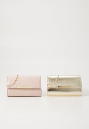 Deux porte-monnaie : à gauche en suède rose doux avec une bandoulière en chaîne dorée ; à droite en matériau doré brillant avec une bandoulière en chaîne dorée. Les deux présentent une étiquette métallique.