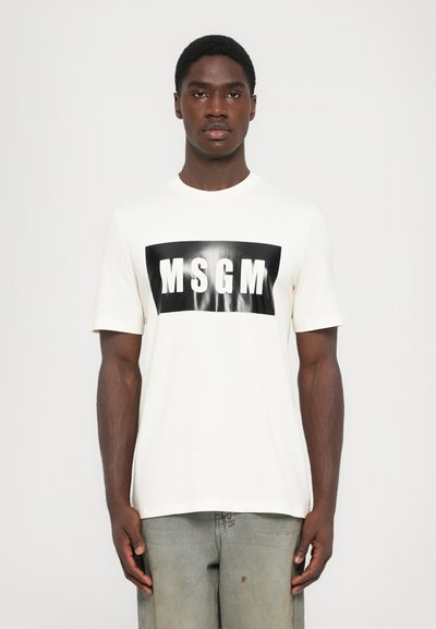 T-shirt en coton blanc avec un graphisme rectangulaire noir comportant "MSGM" en lettres blanches en gras, centré sur le devant. Manches courtes, col rond.