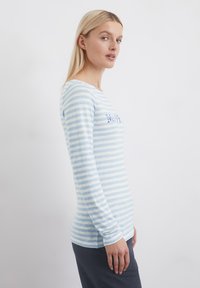 Leichte Langarmbluse mit horizontalen blauen und weißen Streifen, rundem Ausschnitt und gesticktem Text auf der Brust.
