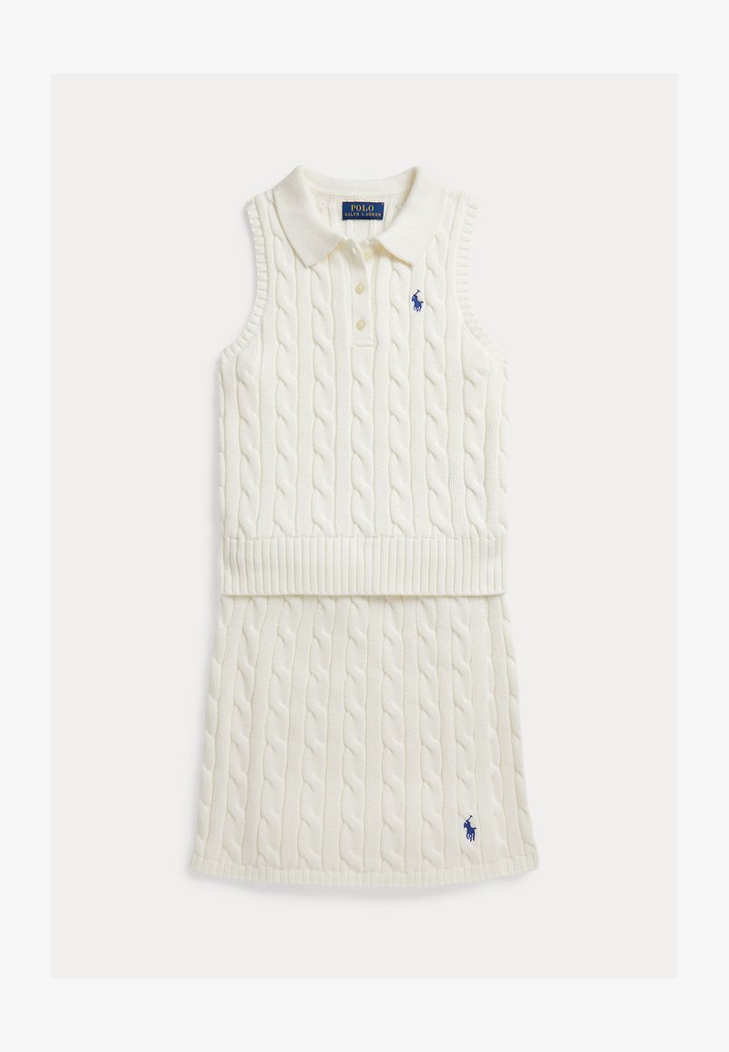 Aduīta bezroku kleita krēmkrāsā ar pītā adījuma tekstūru, ribaina apkakle un jostasvieta. Uz krūtīm ir izšūta zila logo.