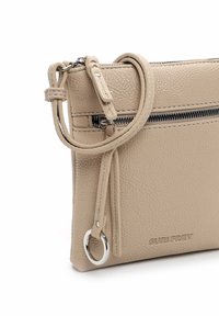 Borsetta a polso in pelle texturizzata beige con tasca anteriore con zip, dettaglio anello in argento e logo "SURI FREY" impresso in basso a destra.